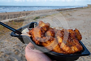 Dutch street seafood, deep fried cod fish fillet with garlic sauce called in Netherlands kibbeling and North sea beach on