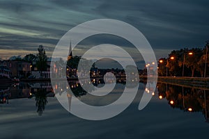 Dutch town with church tower near Gouda with reflections in the water at blue hour