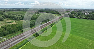 Dutch train passing commuting traveling in forrest grassland nature landscape. Sustainable travel technology by rail