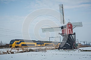 Dutch train and windmill in winter landscape