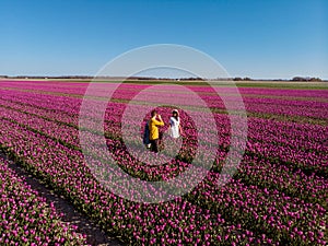 Dutch tulip field, couple in flower field, woman with dress and summer hat in tulips field Netherlands,happy young woman