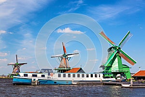 Dutch typical landscape. Traditional old dutch windmills with cruise ship and blue sky in the Zaanse Schans village, Netherlands.