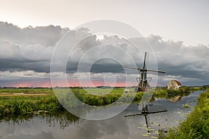 Dutch windmill against an upcoming stormy sky at sunset