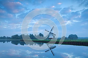 Dutch windmill close to river during calm sunrise