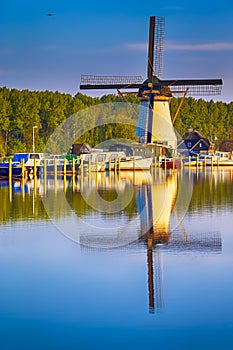 Dutch Windmill In Front of The Canal With Moored Motorboats Located in Traditional Village in The Netherlands. Shot at Kinderdijk