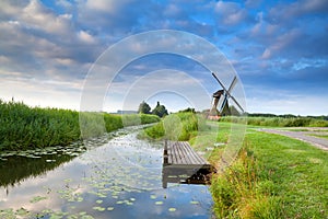 Dutch windmill by river with reflected blue sky