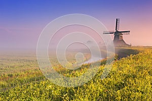 Dutch windmill at sunrise on a foggy morning