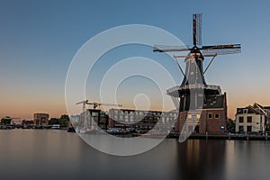 Dutch windmill, in the town of Haarlem, at sunset. The water is smooth, due to a long shutter speed