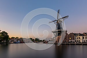 Dutch windmill, in the town of Haarlem, at sunset. The water is smooth, due to a long shutter speed