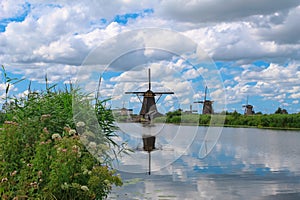 Dutch windmills reflected in water blue cloudy sky