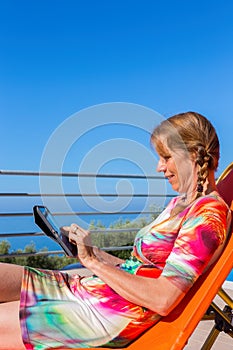 Dutch woman  reading tablet on sunlounger