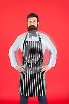 On duty in kitchen. Hipster cafe concept. Man with beard cook hipster apron. Hipster chef cook red background. Bearded