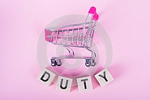 DUTY - word on wooden cubes, on a pink background with a shopping trolley