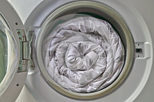 Duvet rolls inside washing machine , Cleaning white blanket.