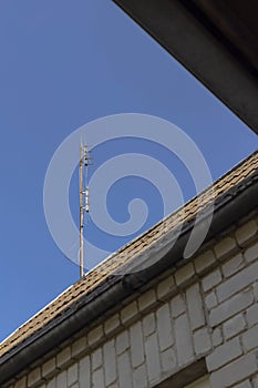 DVB-T antena on the house roof in a blue sky background.