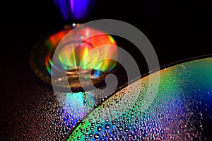 DVD and CD disc with water drops colour background.