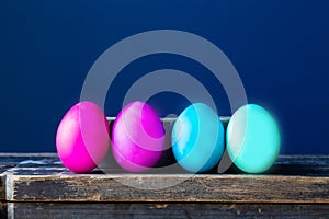 Dyed colorful easter eggs pastel colors near blue wall, modern neon colors spring concept