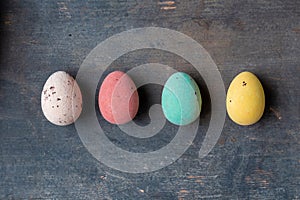 Dyed colorful easter eggs in a row on a vintage wooden background texture, soft pastels modern design