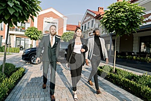 Dynamic Business team, Caucasian woman and man, African man, hurry to outdoor meeting, black car and modern office