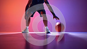 Dynamic display of athleticism. Skillful male basketball player showing dribbling technique with ball on gradient red