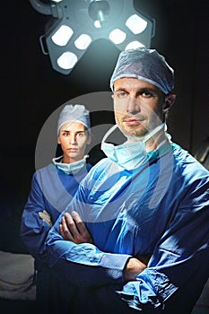 Dynamic doctoring duo. Cropped portrait of two doctors against a dark background.