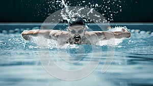 Dynamic and fit swimmer in cap breathing performing the butterfly stroke