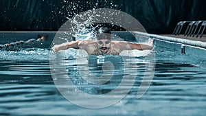 Dynamic and fit swimmer in cap breathing performing the butterfly stroke