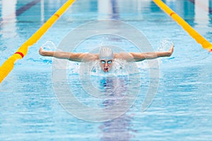 Dynamic and fit swimmer in cap breathing performing the butterfly stroke