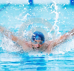 Dynamic and fit swimmer in cap breathing performing the butterfly stroke