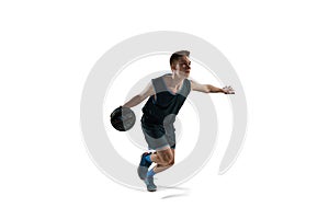 Dynamic image of young man, athlete running with ball, playing basketball isolated against white background