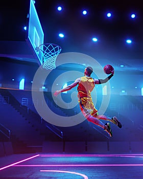 Dynamic image of young man, basketball player in motion, throwing ball into basketball hoop in a jump over neon colored