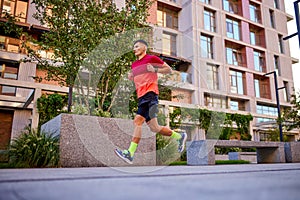 Dynamic image of young muscular man, athlete in motion running along the empty street, training outdoors