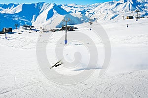 Dynamic picture of a skier on the piste in Alps fall down hard in snow. Active winter holidays, skiing downhill in sunny day.Ski