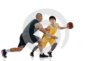 Dynamic portrait of two young basketball players playing basketball isolated on white studio background. Motion