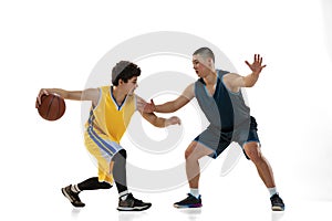 Dynamic portrait of two young basketball players playing basketball isolated on white studio background. Motion