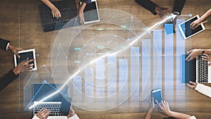 Business Professionals Analyzing Growth Data on Tablets and Laptops with Graphs and Charts on Wooden Table in Modern