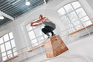 Dynamic shot of fit athlete jumping over cross box in fitness club