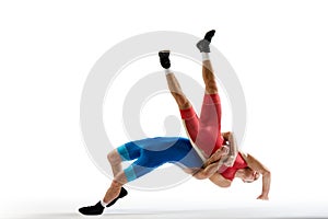 Dynamic shot of two professional Greco-Roman wrestlers in red and blue uniform wrestling against white studio background