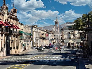 Dynamic street view of Madero Street in Morelia, featuring historic colonial architecture and daily urban life against a mountain