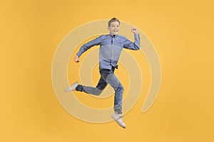 Dynamic teen boy jumping in air against yellow studio background