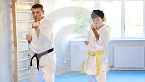 Dynamic underage boy performing fighting positions in row during karate courses