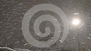 Dynamic video of falling snow in the light of a street lamp. Seasonal snow storm, blizzard