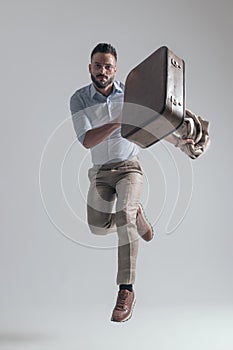 Dynamic young businessman holding bag and jacket while jumping