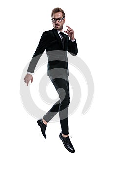 Dynamic young man in black suit jumping in the air