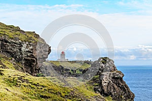 In a nice view between the rocks on the volcanic cape Dyrholaey in the southernmost part of Iceland stands the lighthouse building photo