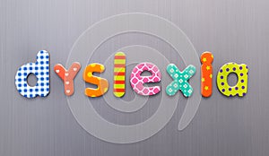 Dyslexia word spelled out in bright colorful patterened letters on brushed metal background
