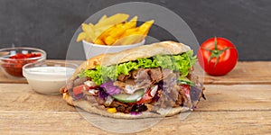 DÃÂ¶ner Kebab Doner Kebap fast food in flatbread with fries on a wooden board panorama photo