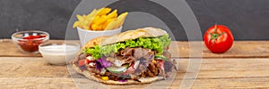 DÃÂ¶ner Kebab Doner Kebap fast food in flatbread with fries on a wooden board panorama photo
