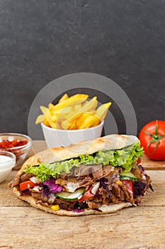DÃÂ¶ner Kebab Doner Kebap fast food in flatbread with fries on a wooden board portrait format photo