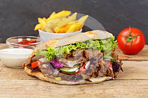 DÃÂ¶ner Kebab Doner Kebap fast food in flatbread with fries on a wooden board photo